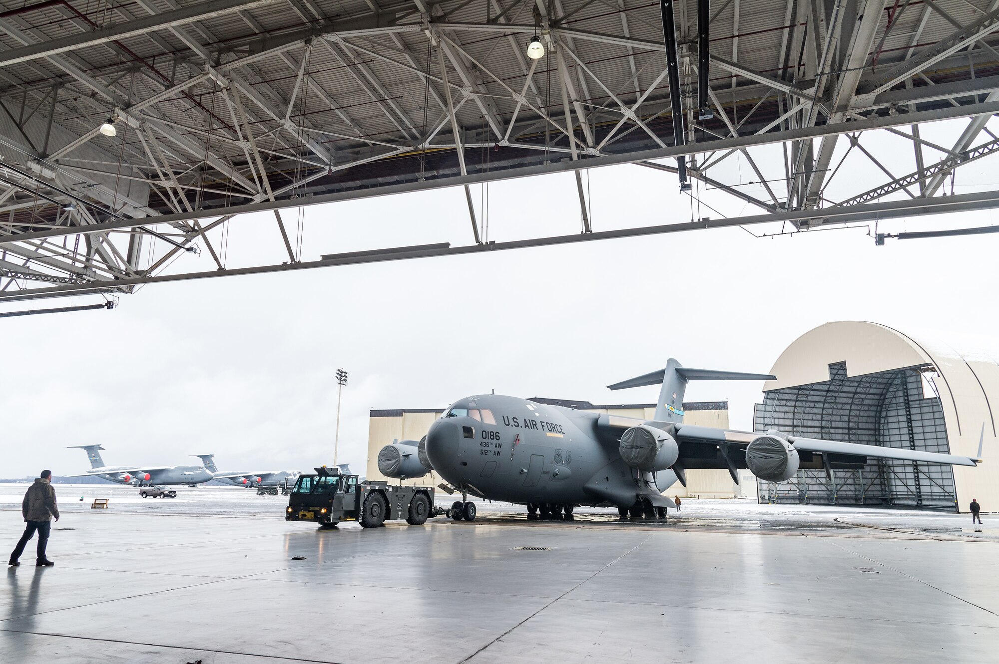 A maintenance tow team from the 736th Aircraft Maintenance Squadron, tow a C-17 Globemaster III from the flight line to a hangar to facilitate maintenance out of the weather at Dover Air Force Base, Delaware, Feb. 7, 2021. As snow fell, the base continued normal operations and prepared for additional snowfall. (U.S. Air Force photo by Roland Balik)