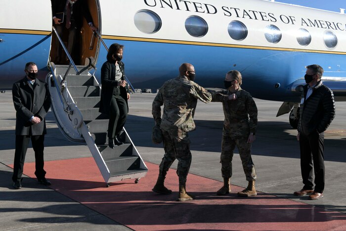 Photo shows man and woman saluting outside an aircraft.