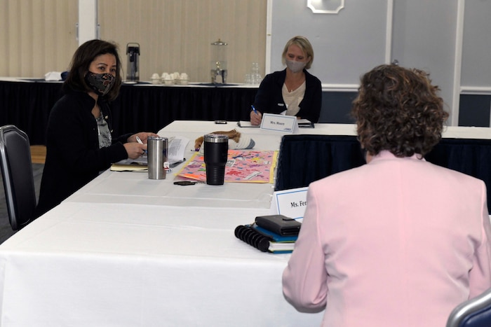 Photo shows three women sitting around a group of tables.