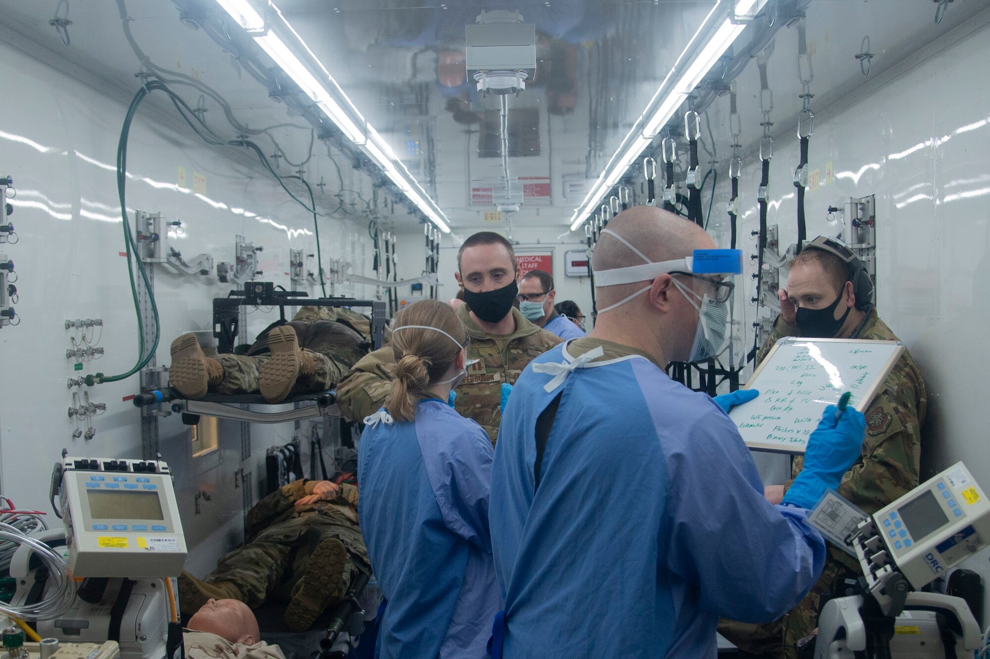 U.S. Air Force Airmen assigned to the 10th Expeditionary Aeromedical Evacuation Flight write notes about patient care and speak with their instructors while inside a Negatively Pressurized Conex during training at Ramstein Air Base, Germany, Jan. 30, 2021.