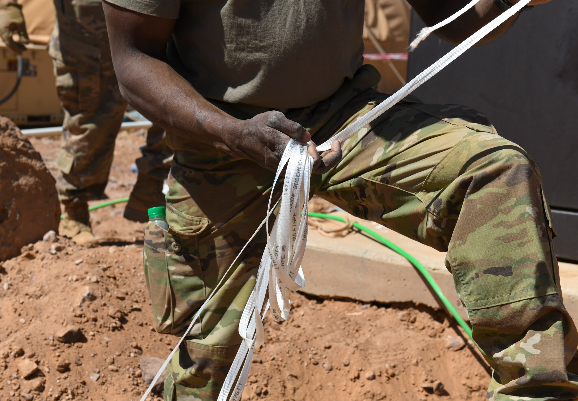 U.S. Air Force Tech. Sgt. Edward George, 724th Expeditionary Air Base Squadron civil engineer electrical systems craftsman, unravels mule tape while replacing old polyvinyl chloride conduit and wire at Nigerien Air Base 201, Agadez, Niger, Feb. 4, 2021. Mule tape is used for pulling cables through electrical conduits. (U.S. Air Force photo by Senior Airman Gabrielle Winn)