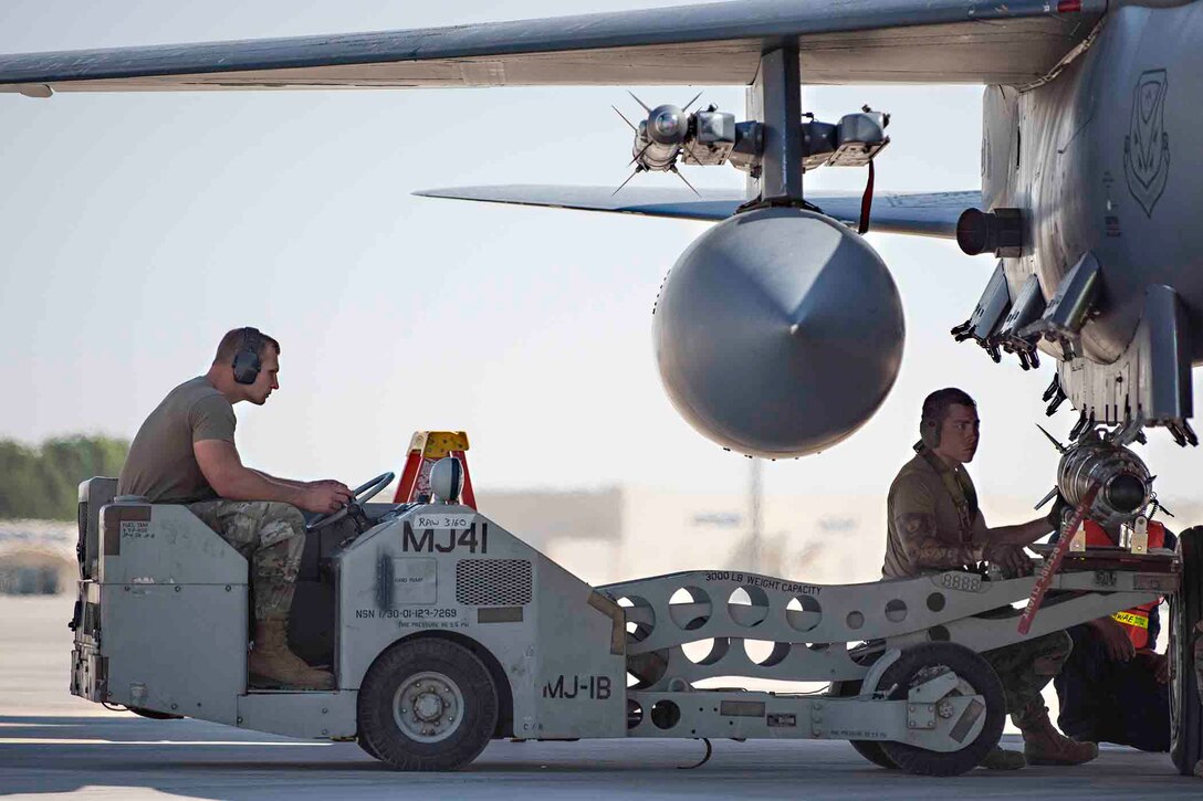 Two airmen load a munition on an Air Force aircraft.