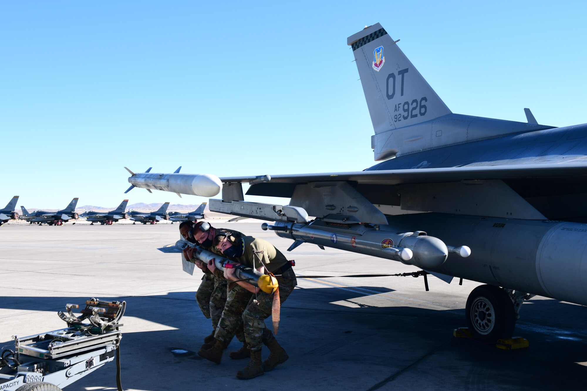 Senior Airman Javel Singleton, Tech Sgt. Jaime Hastings, and Senior Airman Kaleb Moyer, 926th Aircraft Maintenance Squadron, removes a weapon from an F-16, Feb. 6, at Nellis Air Force Base, Nevada.