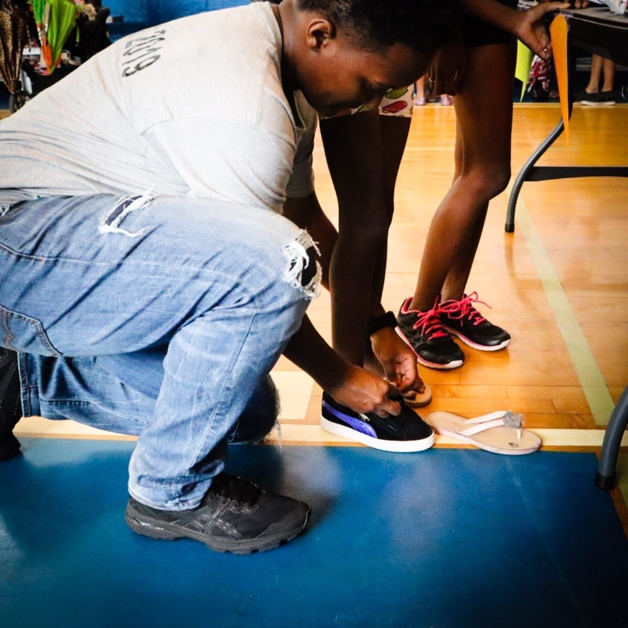 A woman bends down to tie a child's shoe