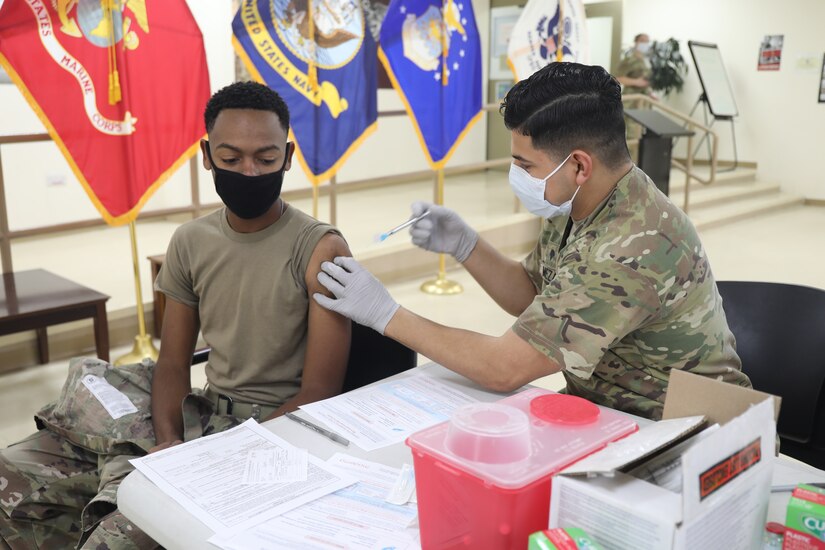 Spc. Michael Meza, healthcare specialist, 228th Combat Support Hospital, administers the Moderna COVID-19 vaccine to Spc. Sarrod Hearn, radiology specialist, 228th Combat Support Hospital, at Camp Arifjan, Kuwait, Jan. 18, 2021. Camp Arifjan is utilizing a phased distribution of the vaccine, as specified by the Department of Defense, beginning with medical personnel and first responders.