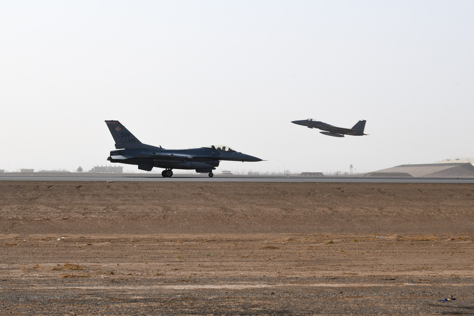 An F-16C Fighting Falcon, assigned to the 77th Expeditionary Fighter Squadron, taxis on the runway while a Royal Saudi Air Force F-15 Eagle takes off, Feb. 2, 2021, at King Faisal Air Base, Kingdom of Saudi Arabia.