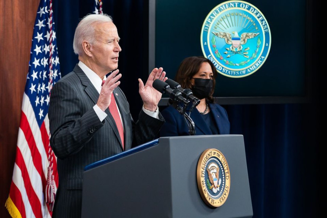 President Joe Biden speaks while Vice President Kamala Harris stands to his right.