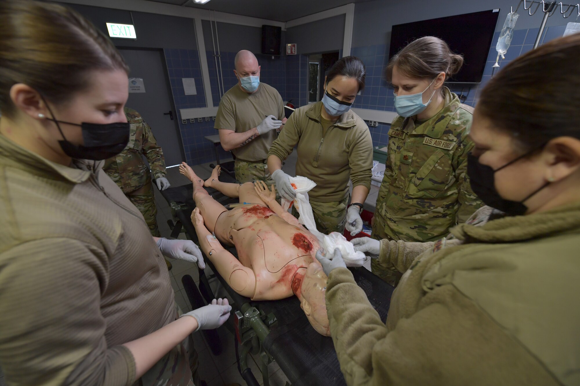 Airmen standing around a simulated medical patient mannequin.
