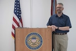 Matt Smith, the Civilian of the Quarter for April - June 2020, poses behind his teaching podium Aug. 11, 2020, aboard Training Center Cape May, New Jersey. Our Training Center staff serve the American public by leveraging their talent and passion to produce mission-ready recruits, and delivering professional, high-quality services to enable future missions for our units, tenants, and regions. (U.S. Coast Guard photo by Petty Officer 2nd Class Shannon Kearney)