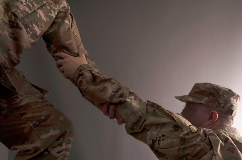 A service member holds the arm of another service member.