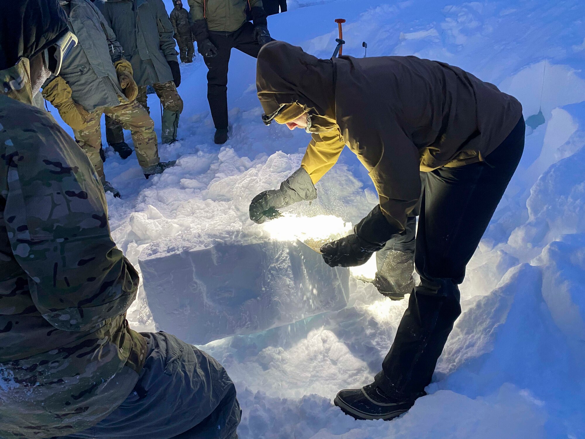 U.S. Air Force Senior Airman Jesse Cash, a 66th Training Squadron, Detachment 1 survival, evasion, resistance and escape (SERE) specialist demonstrates how to cut  out a block of hard-packed snow at Utqiaġvik (Barrow), Alaska, Jan. 11, 2021.