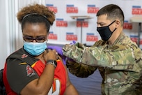Indiana National Guard Staff Sgt. Colin Singleton, Indiana Medical Detachment combat medic specialist, administers a COVID-19 vaccine to Audrey Lee, U.S. Army Financial Management Command accountant, at the Johnson County Armory in Franklin, Indiana, Feb. 5, 2021. Lee was one of several USAFMCOM mission essential personnel who received their first round of vaccines along with more than 100 others that morning. (U.S. Army photo by Mark R. W. Orders-Woempner)