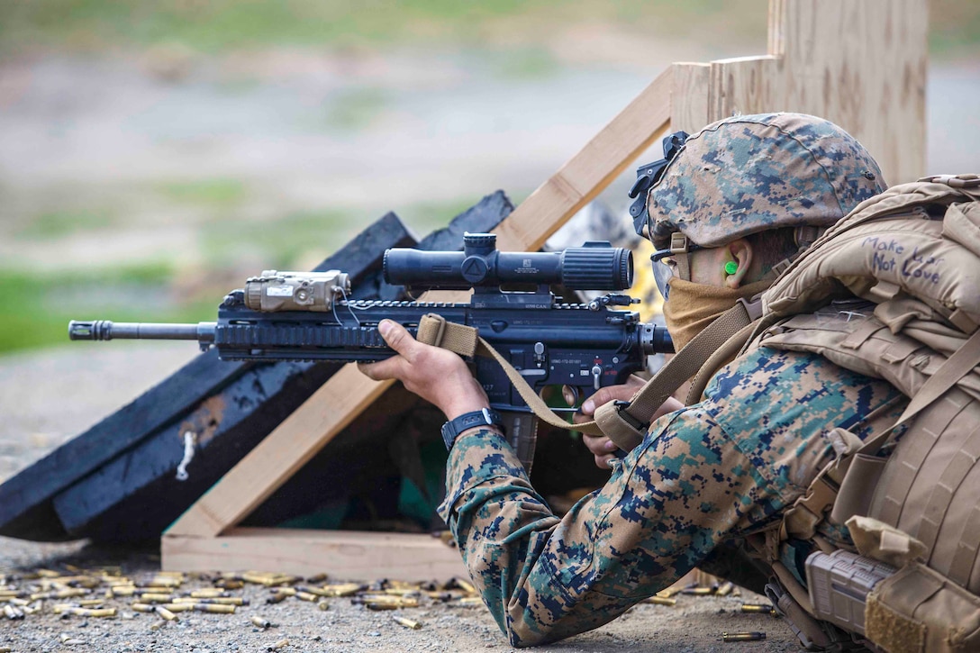 A Marine lies on the ground shooting at targets.