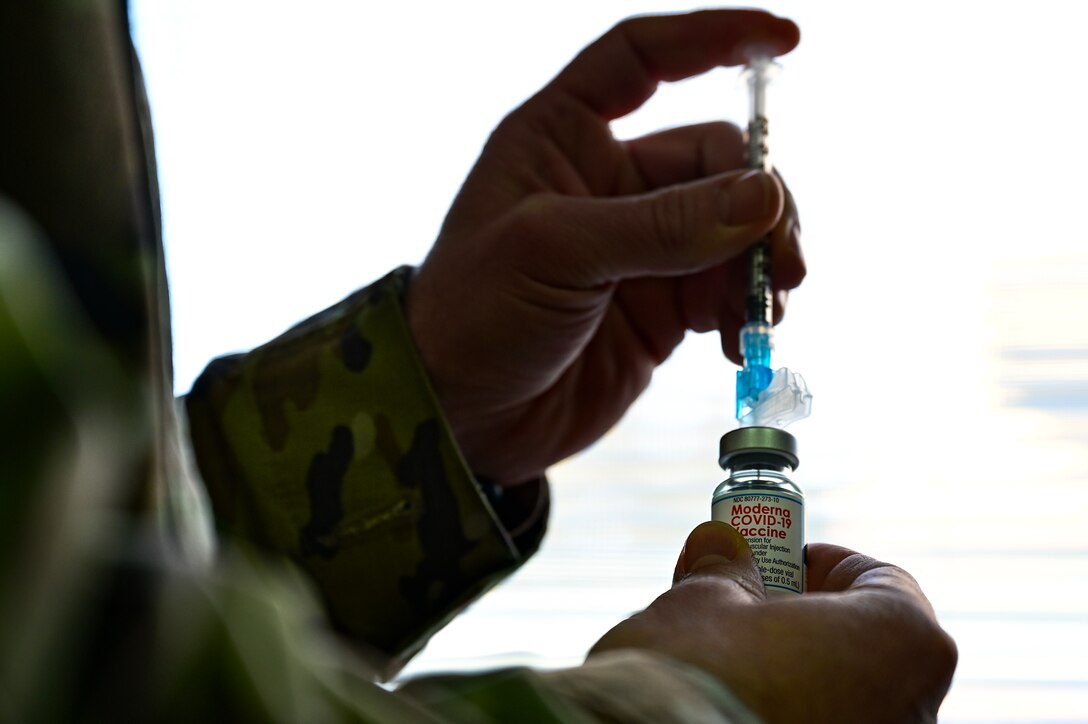 An aeromedical technician prepares to fill a syringe with the COVID-19 vaccine