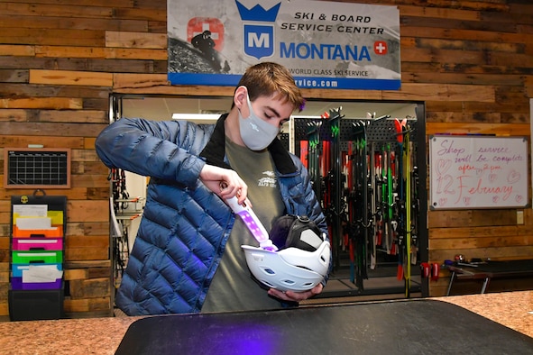 Austin Lynnville, outdoor recreation clerk and ski technician, uses a ultra violet wand to sterilize ski equipment.
