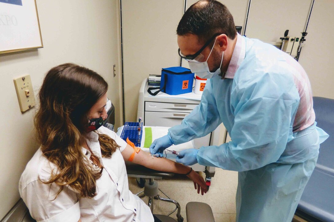 A man draws a blood sample from a woman.