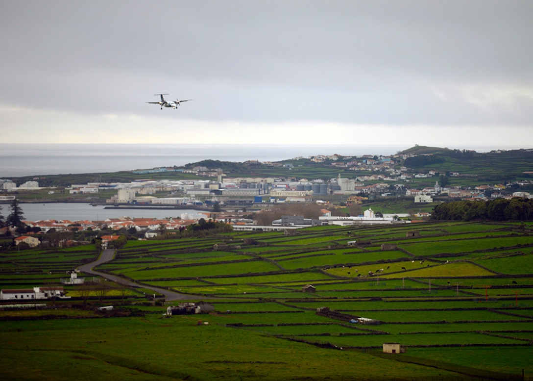 A plane lands in an oceanside village.