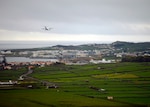 A plane lands in an oceanside village.