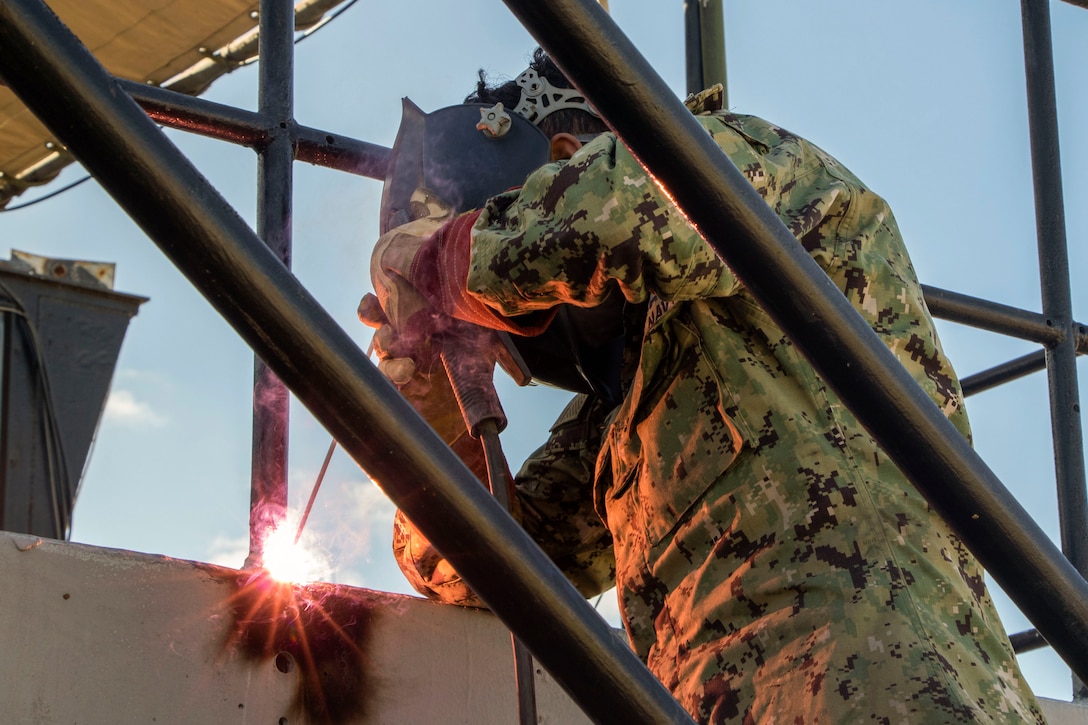 A sailor performs maintenance on a platform.