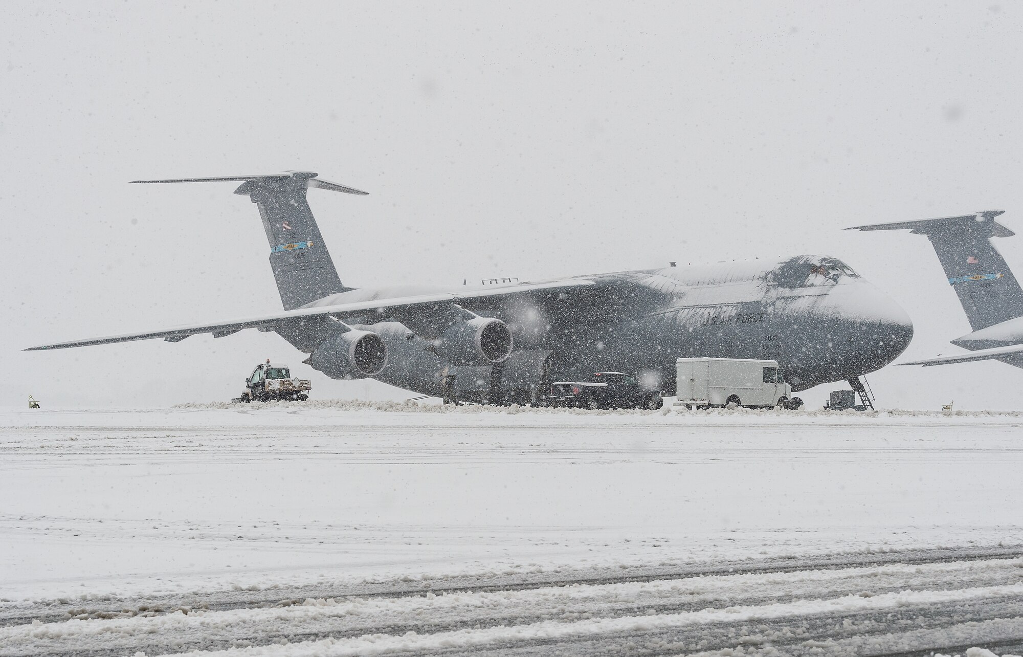 A snow-covered C-5M Super Galaxy being prepared for takeoff sits on the flight line at Dover Air Force Base, Delaware, Feb. 11, 2021. As Winter Storm Roland produced a wintry mix of precipitation, the base continued normal operations and prepared for additional forecast snowfall. (U.S. Air Force photo by Roland Balik)