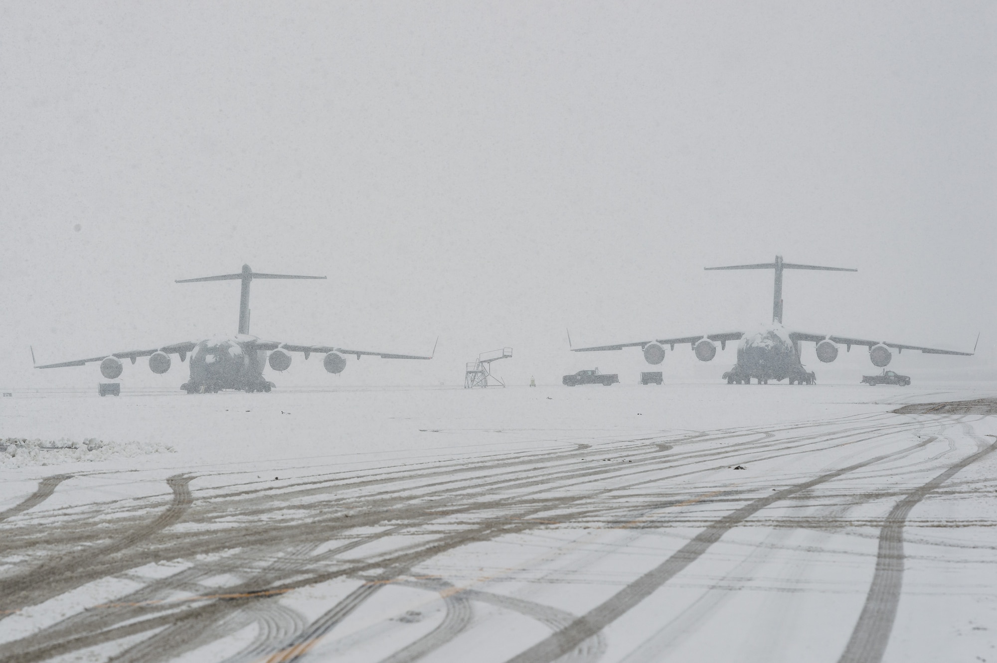 Transient C-17 Globemaster III aircraft sit on the snow-covered flight line at Dover Air Force Base, Delaware, Feb. 11, 2021. As Winter Storm Roland produced a wintry mix of precipitation, the base continued normal operations and prepared for additional forecast snowfall. (U.S. Air Force photo by Roland Balik)