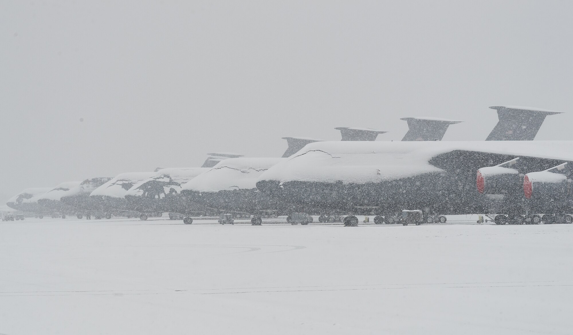 Snow-covered C-5M Super Galaxy aircraft sit on the flight line at Dover Air Force Base, Delaware, Feb. 11, 2021. As Winter Storm Roland produced a wintry mix of precipitation, the base continued normal operations and prepared for additional forecast snowfall. (U.S. Air Force photo by Roland Balik)