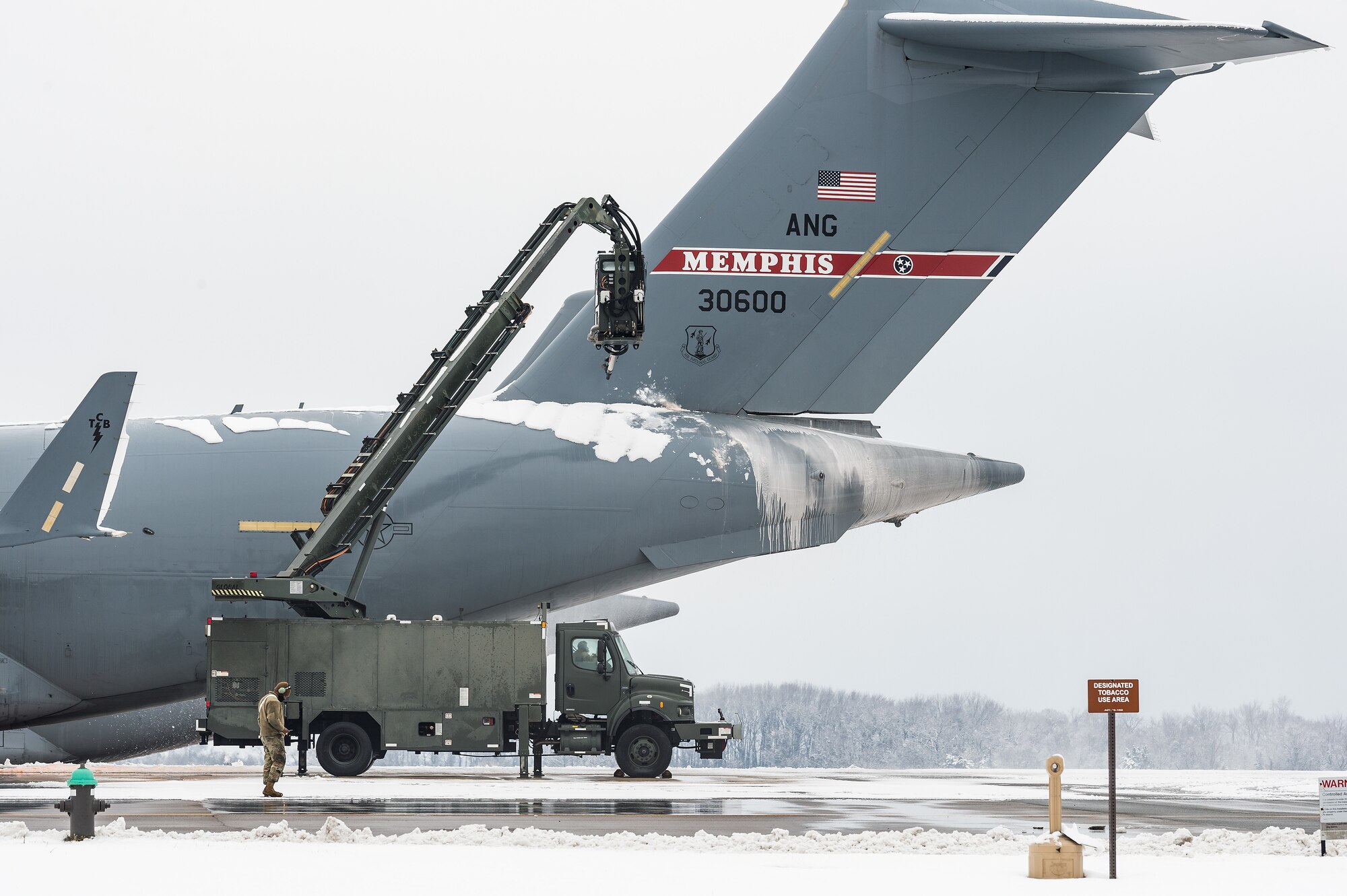 A de-icing vehicle removes snow from the aft fuselage of a transient Tennessee Air National Guard C-17 Globemaster III prior to departing Dover Air Force Base, Delaware, Feb. 11, 2021. As Winter Storm Roland produced a wintry mix of precipitation, the base continued normal operations and prepared for additional forecast snowfall. (U.S. Air Force photo by Roland Balik)