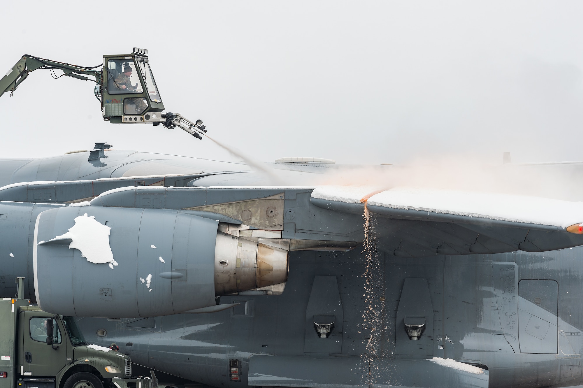 A de-icing vehicle removes snow from the left wing of a transient Tennessee Air National Guard C-17 Globemaster III prior to departing Dover Air Force Base, Delaware, Feb. 11, 2021. As Winter Storm Roland produced a wintry mix of precipitation, the base continued normal operations and prepared for additional forecast snowfall. (U.S. Air Force photo by Roland Balik)