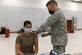 Air Force colonel administers COVID-19 vaccine to female Airman.