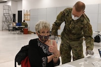 Woman gives "thumbs up" while receiving COVID-19 vaccine.
