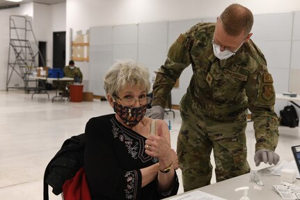 Woman gives "thumbs up" while receiving COVID-19 vaccine.