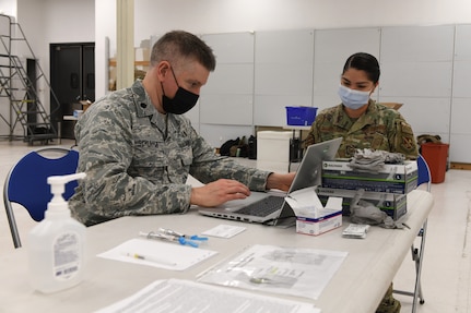 Air Force colonel administers COVID-19 vaccine to female Airman.