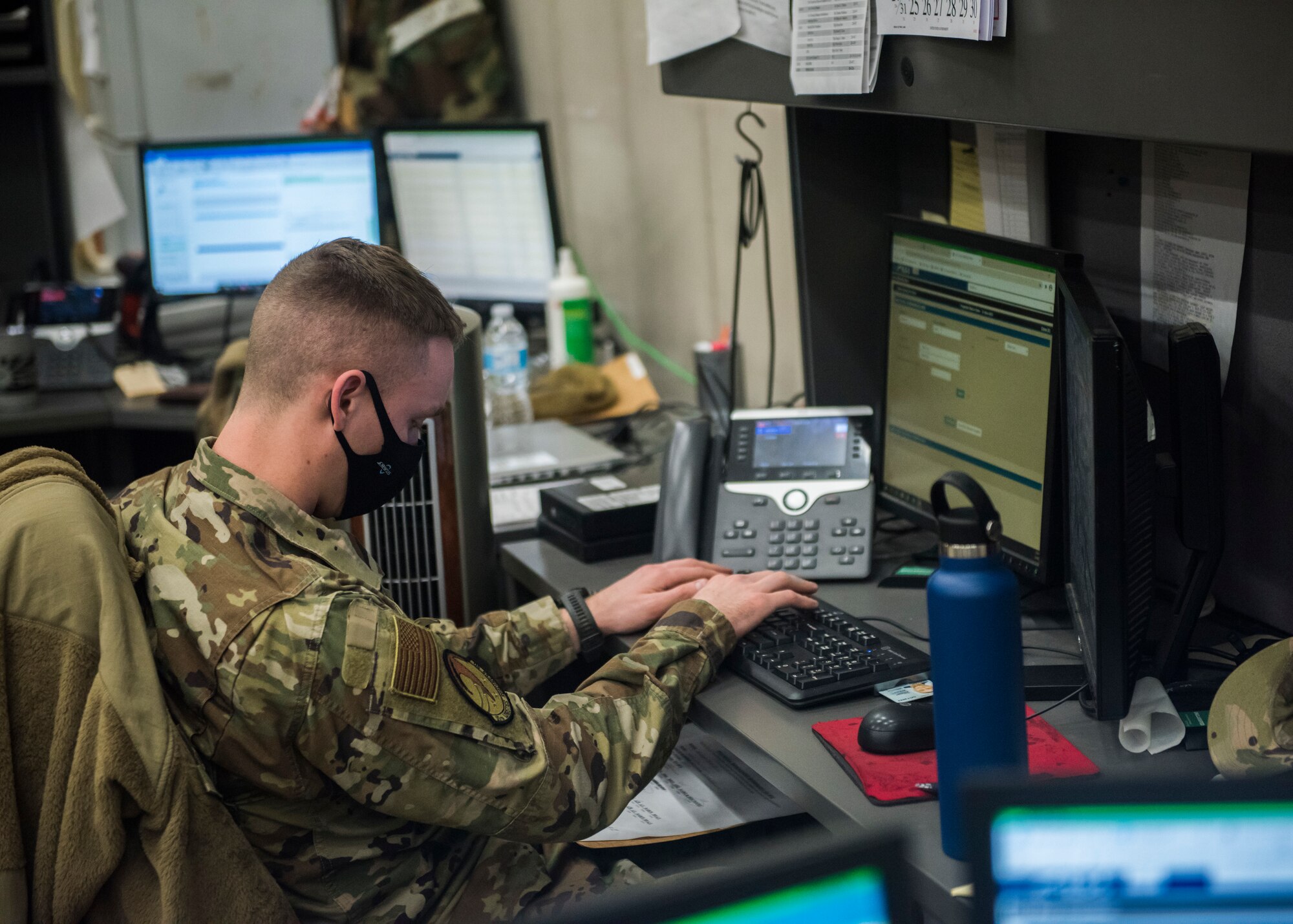 Man in uniform sitting at a desk typing on a computer