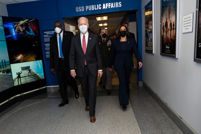 President Joe Biden and Vice President Kamala Harris walk down a hallway in the Pentagon with other leaders.