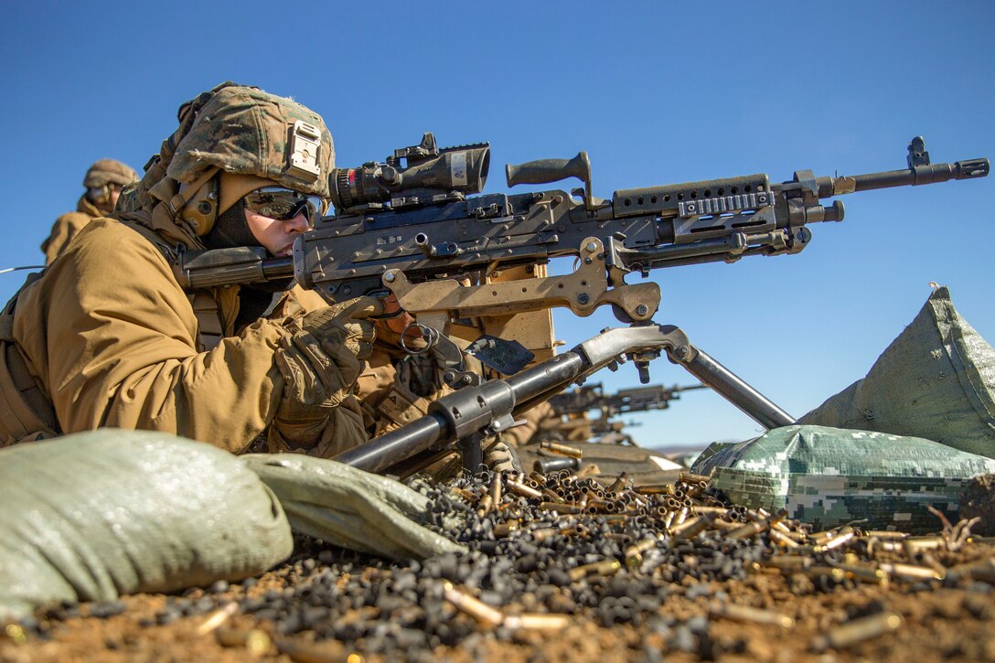 A sailor aims a weapon while lying on the ground.