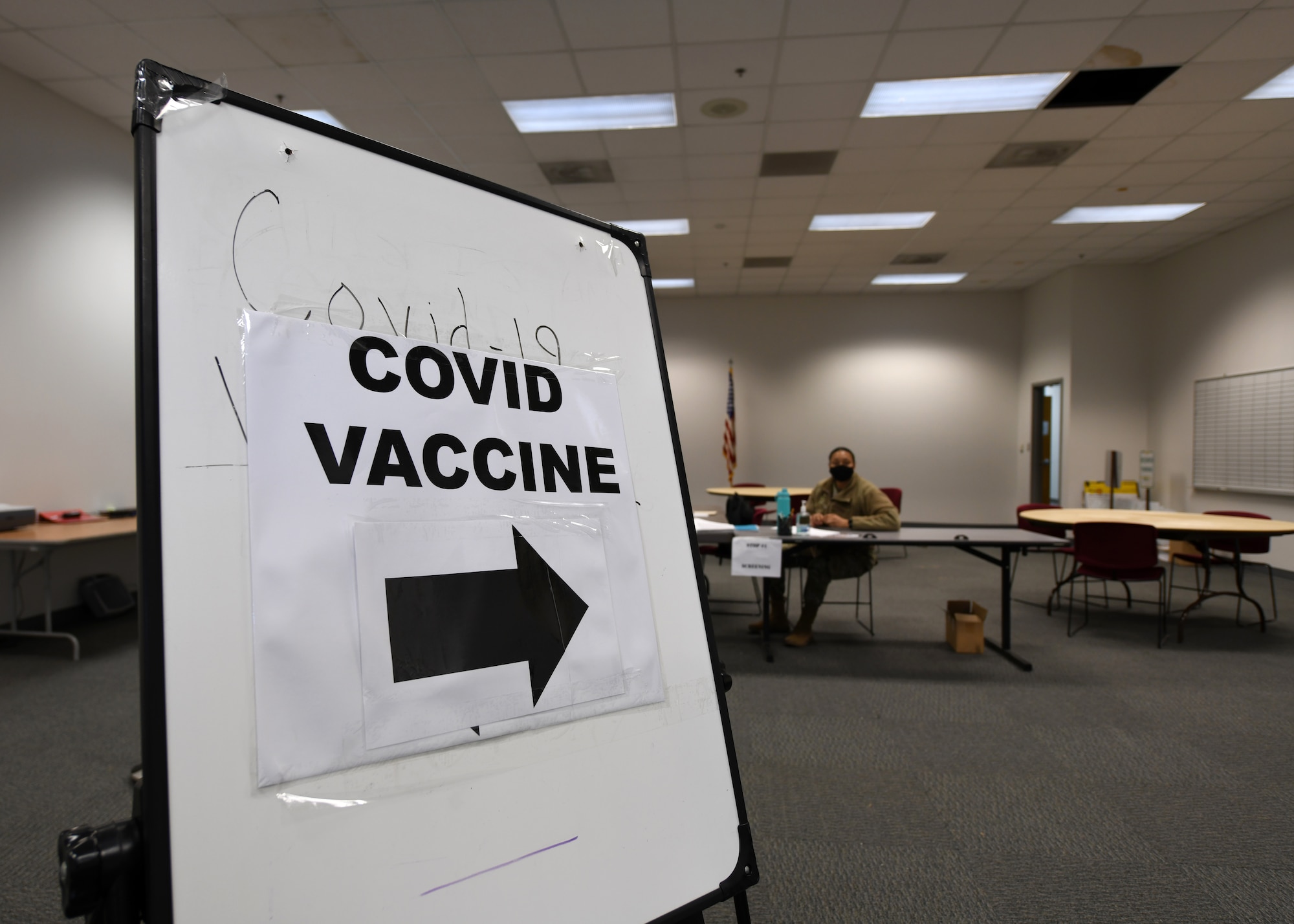 A sign reading "COVID Vaccine" with a black arrow pointing to the right.
