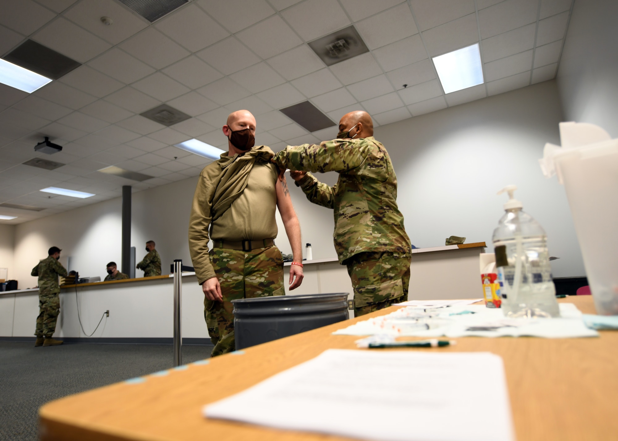 A US Air Force Master Sgt. administers a shot to the left arm of an Airman.