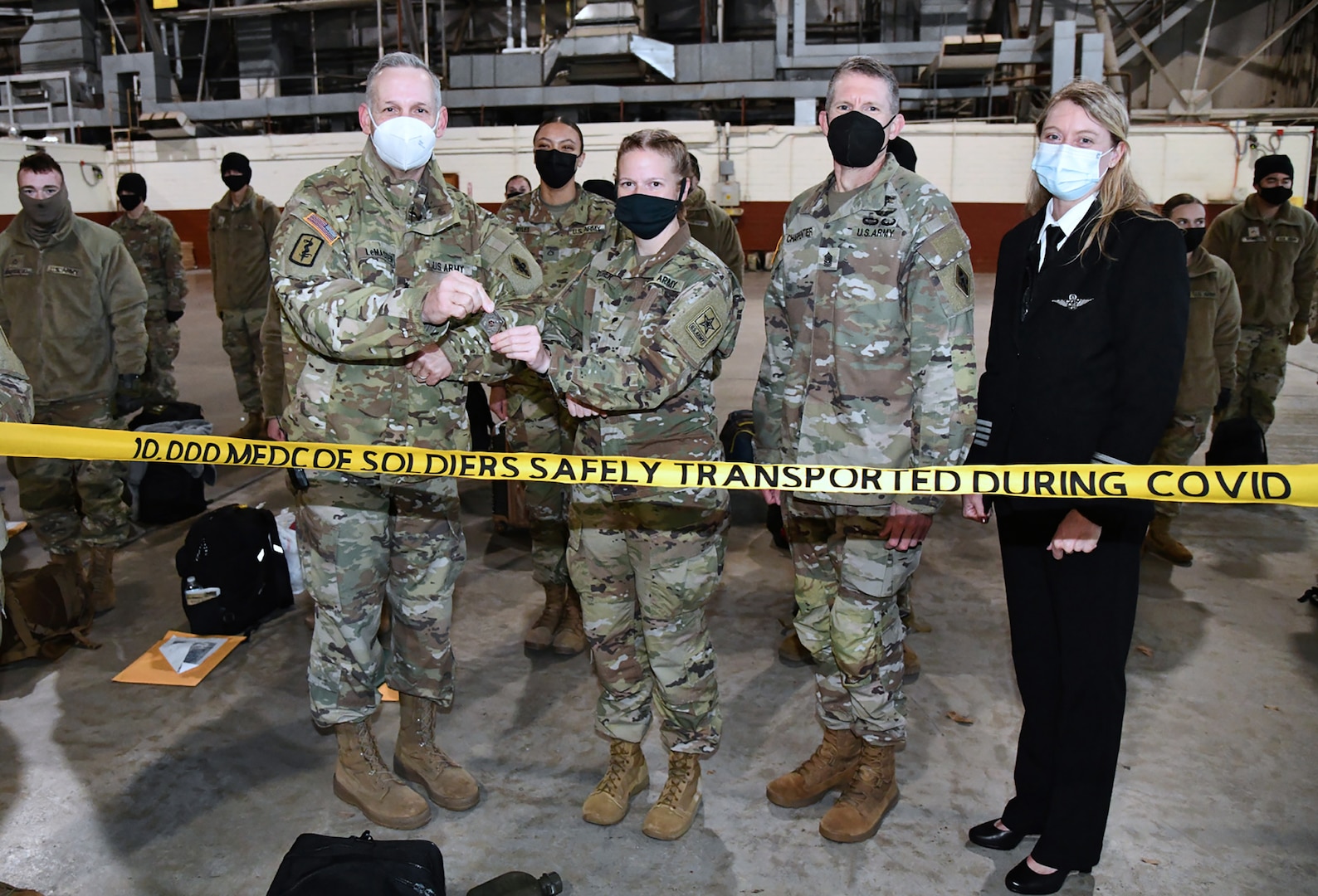 Maj. Gen. Dennis LeMaster, U.S. Army Medical Center of Excellence commanding general, presents a coin to Spc. Angela Thresher, a 68W Combat Medic from Washington State who was identified as the 10,000th Soldier to depart from MEDCoE in a controlled manner as part of the COVID-19 pandemic. She departs Joint Base San Antonio-Fort Sam Houston for her follow-on duty assignment at Tripler Army Medical Center, Hawaii. Also pictured is MEDCoE Command Sgt. Maj. Clark Charpentier.
