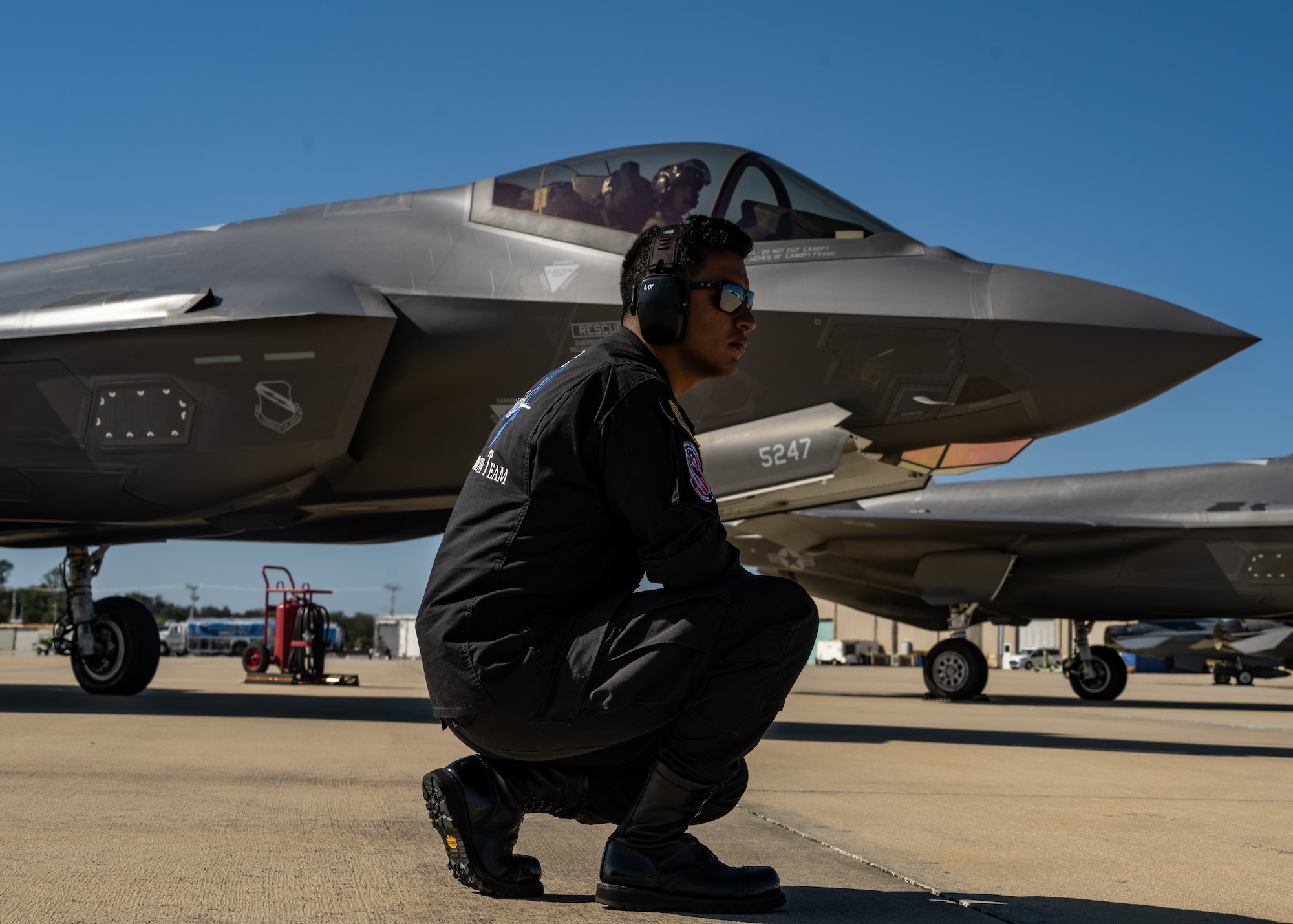 An Air Force maintainer kneels in front of an F-35