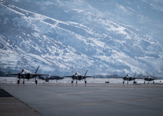 F-35s on a flightline with mountains in the background
