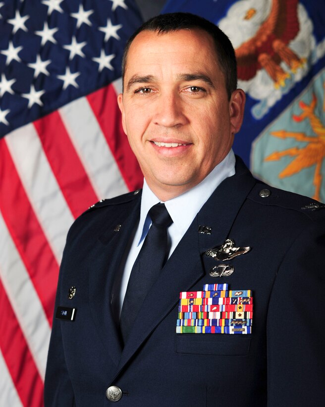 Col. Bryan Stone posing in front of an American flag on his right, and an Air Force flag on his left.