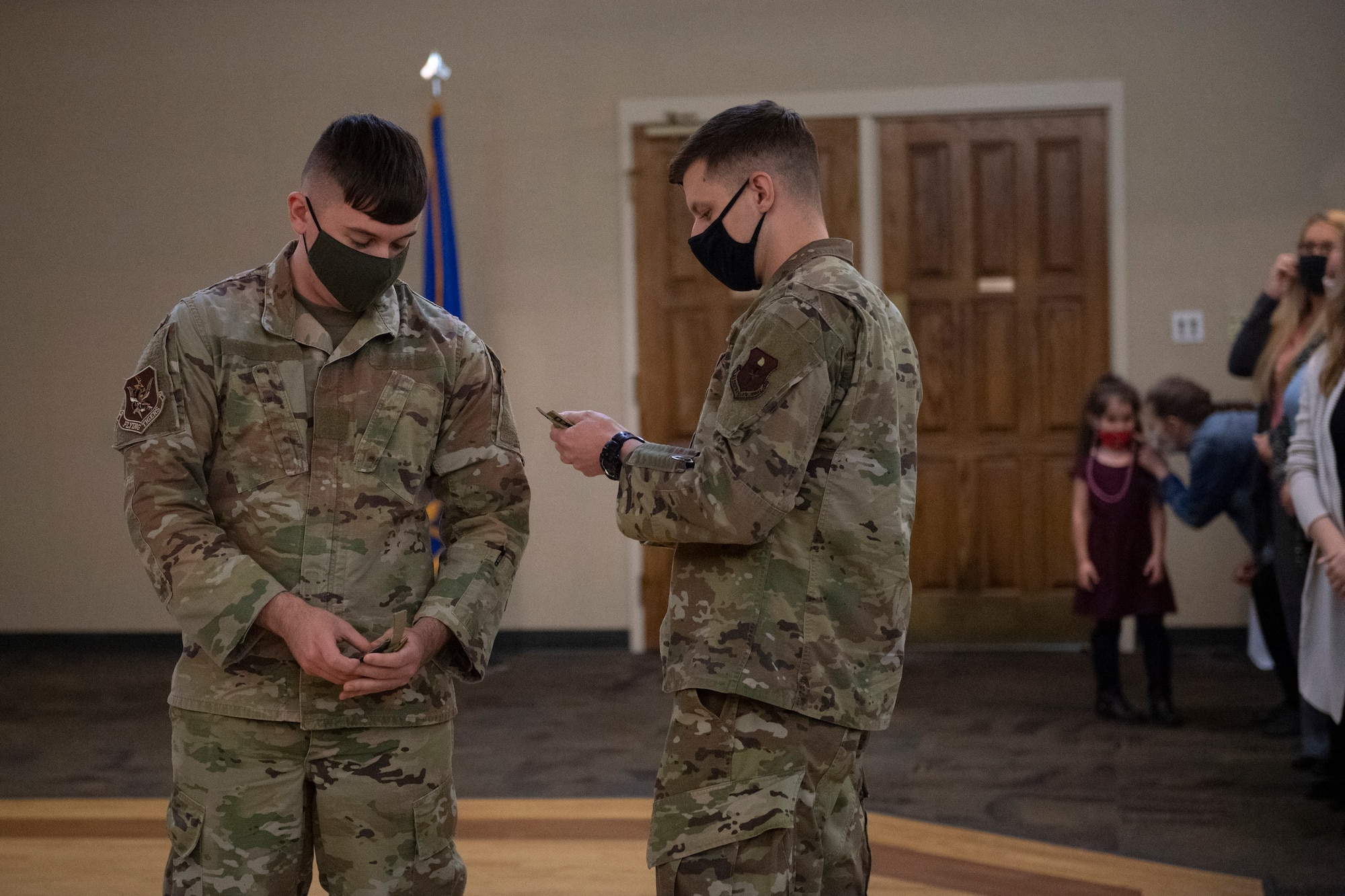 A photo of an Airman putting a patch on another Airman's uniform.