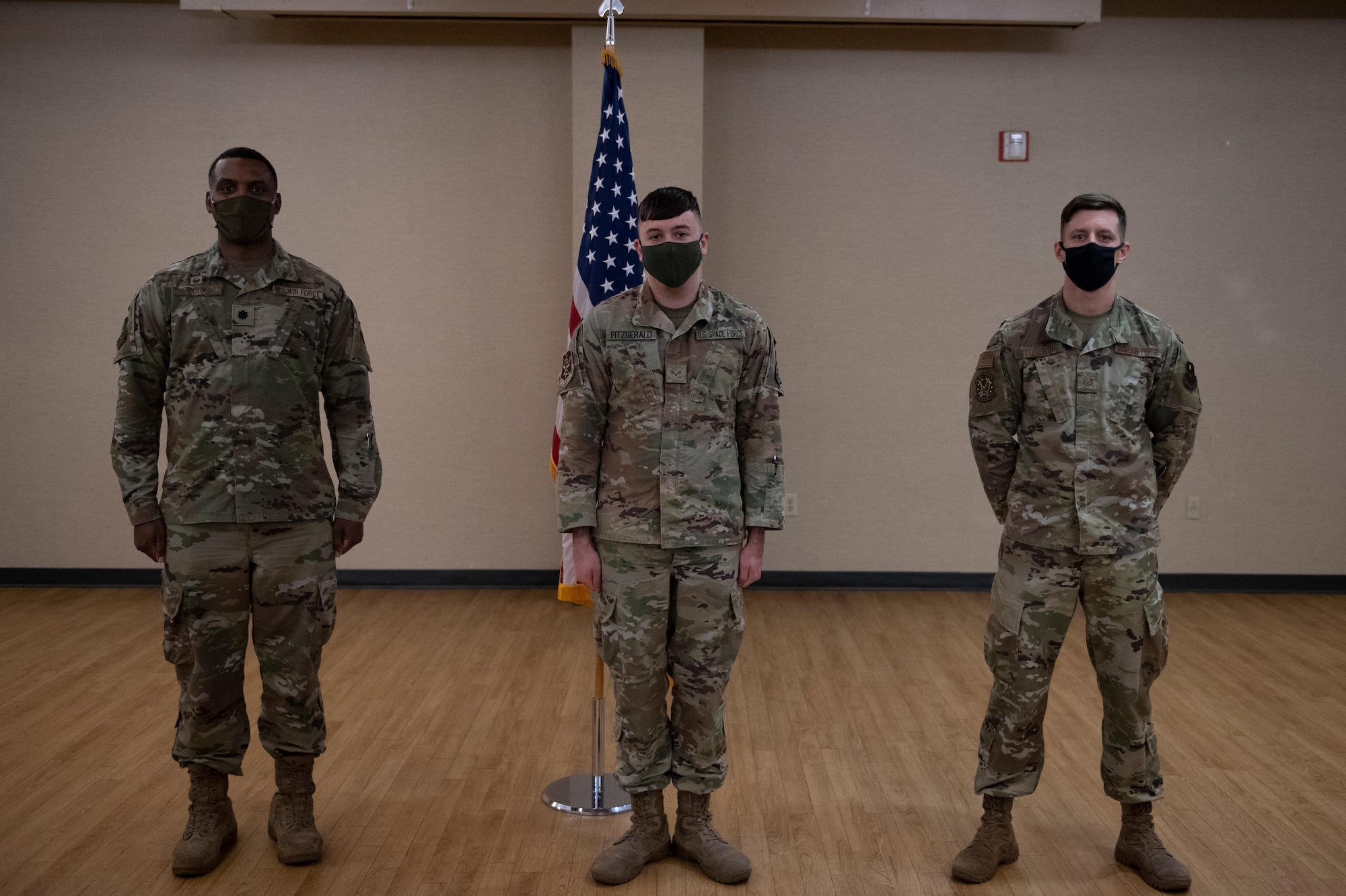 A photo of Airmen posing in front of an American flag.