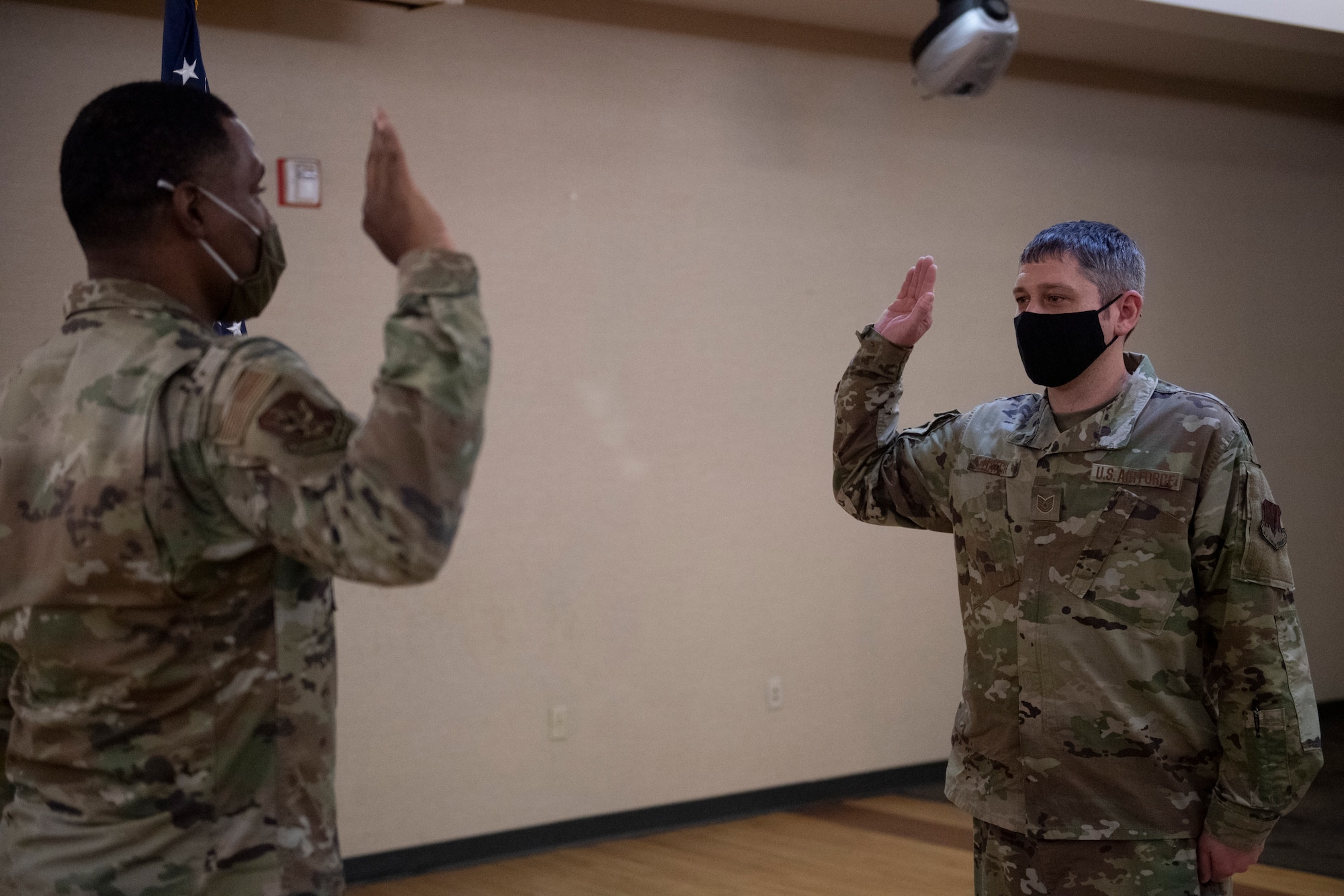 A photo of two Airmen raising their right are during an enlistment.