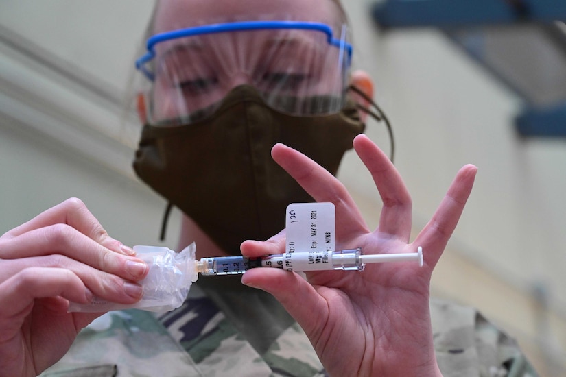 Lady sticks a needle into a plastic sleeve.