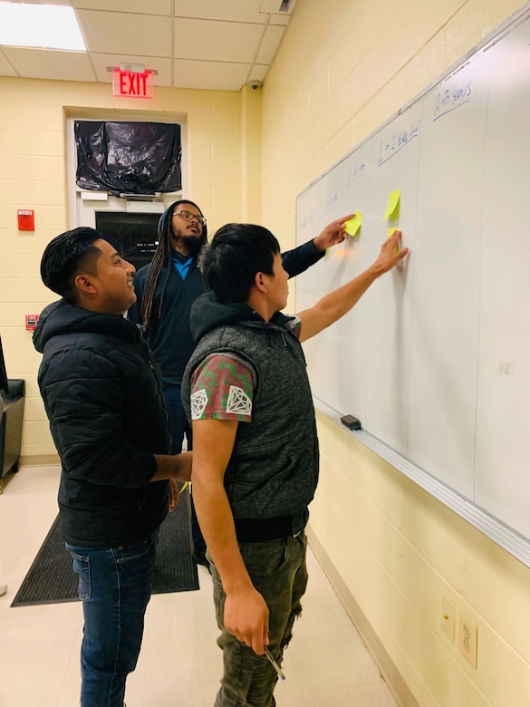 Students point to a marker board.