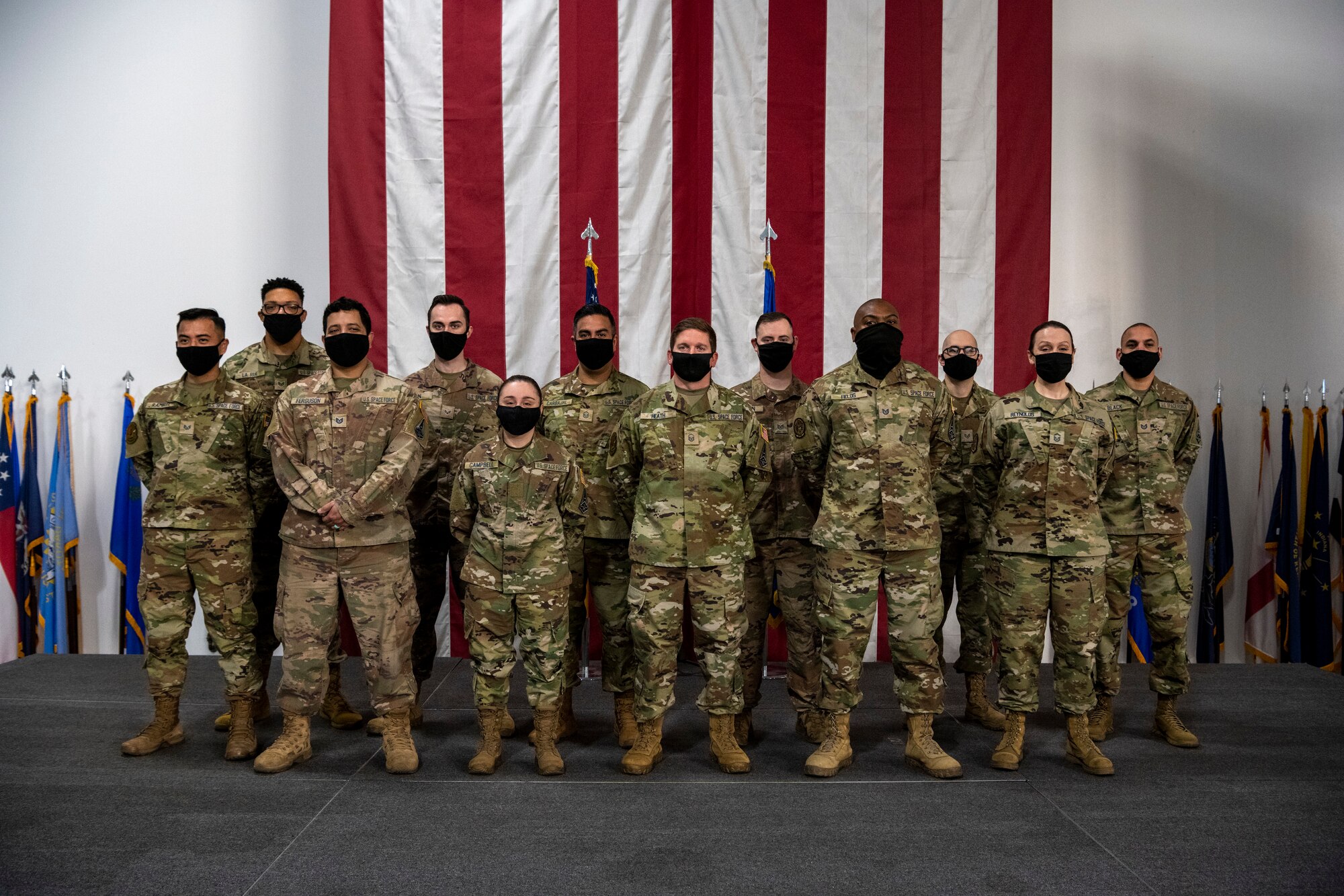 Men and women stand together for a group photo wearing masks.