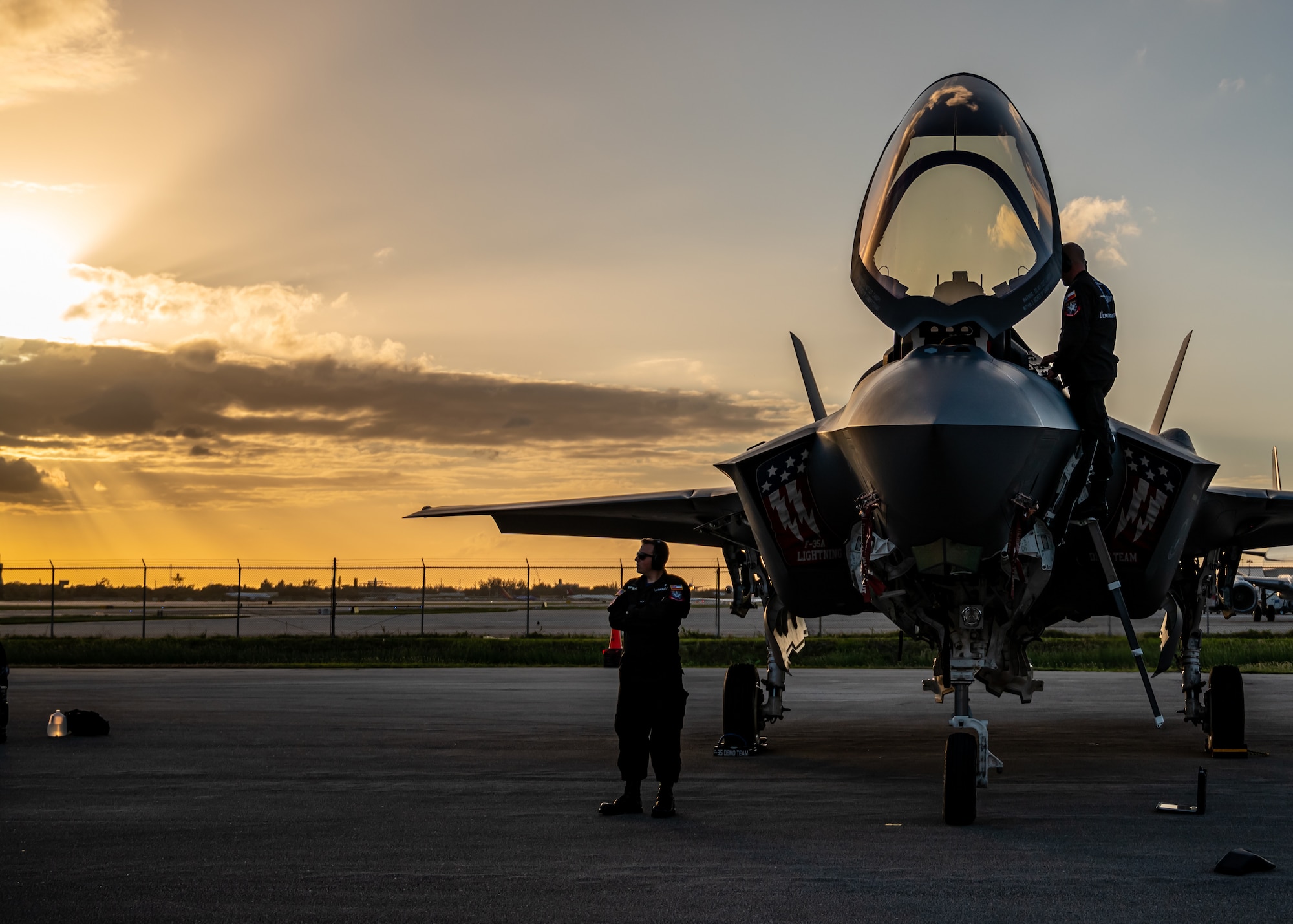 Maintainers work on an F-35 while the sun sets.