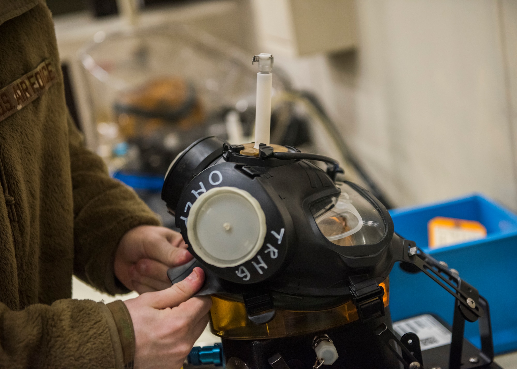 Man in uniform fitting a gas mask to a machine