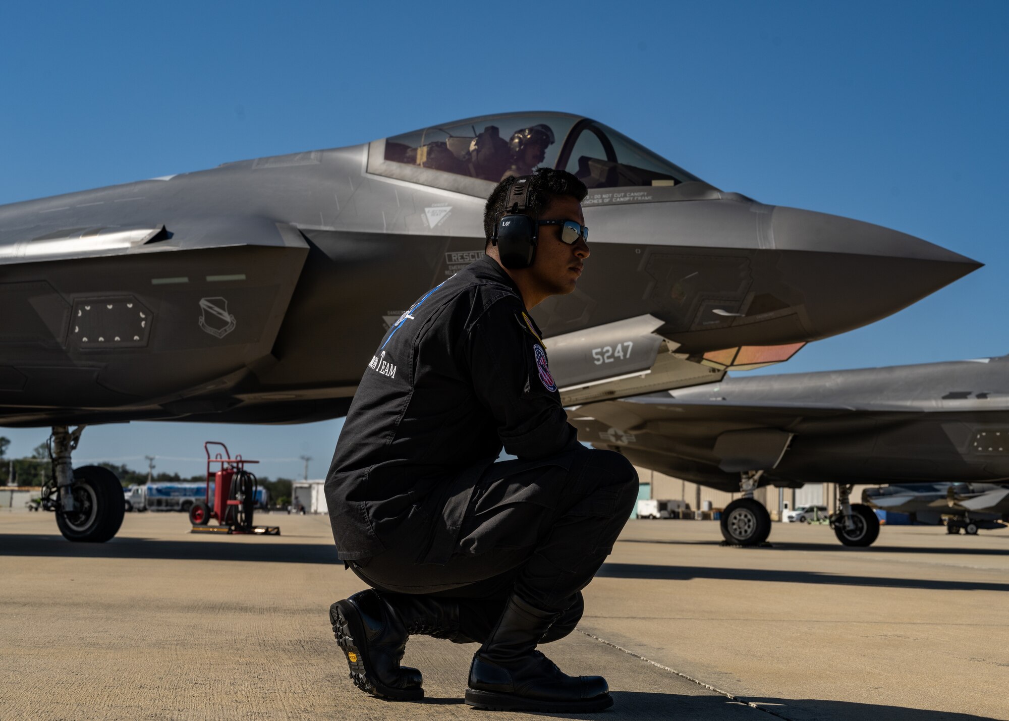 An Air Force maintainer kneels in front of an F-35